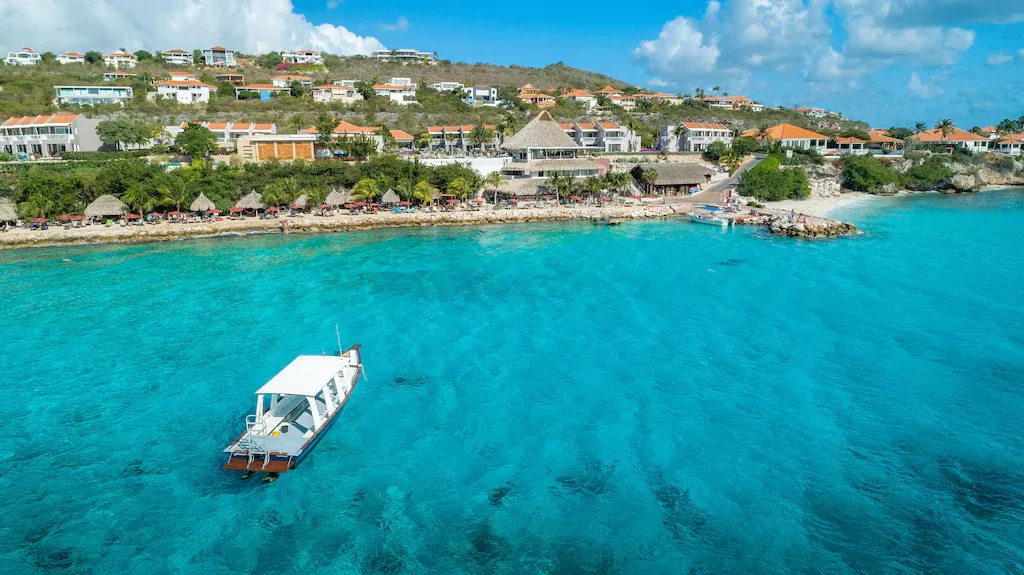 een blauwe zee met een boot op curacao coral estate